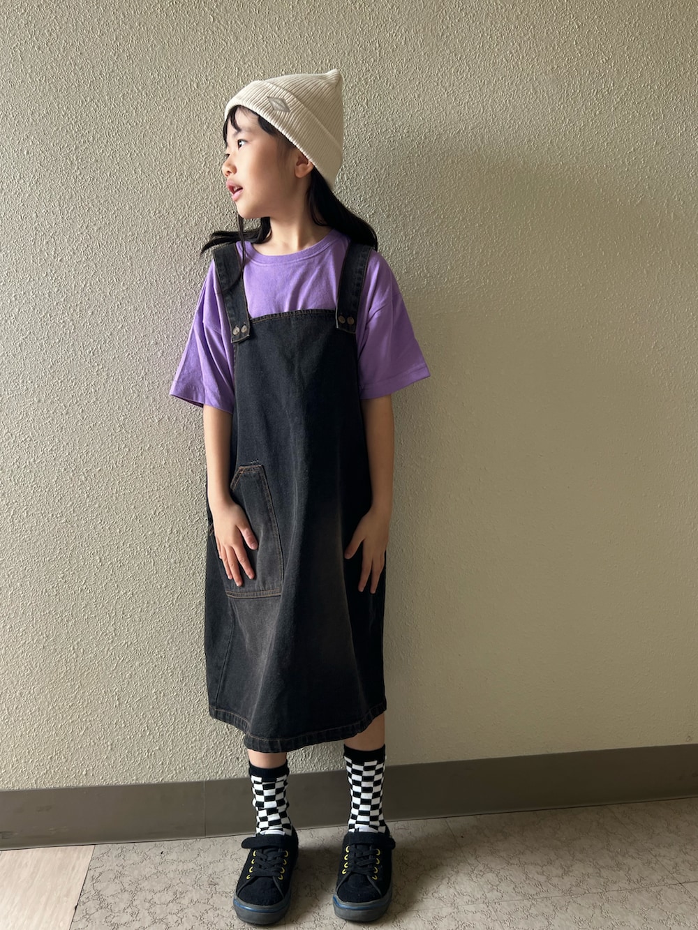 パープル系のTシャツ/カットソー、ブラック系のジャンパースカート、ブラック系のスニーカーを着用したキッズの春コーディネートの3枚目の写真