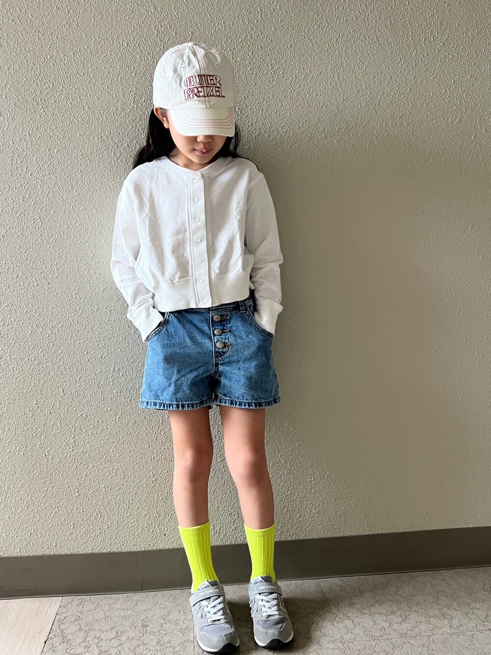 グレー系のスニーカー、ブルー系のデニムパンツ、ホワイト系のキャップを着用したキッズの春コーディネートの2枚目の写真