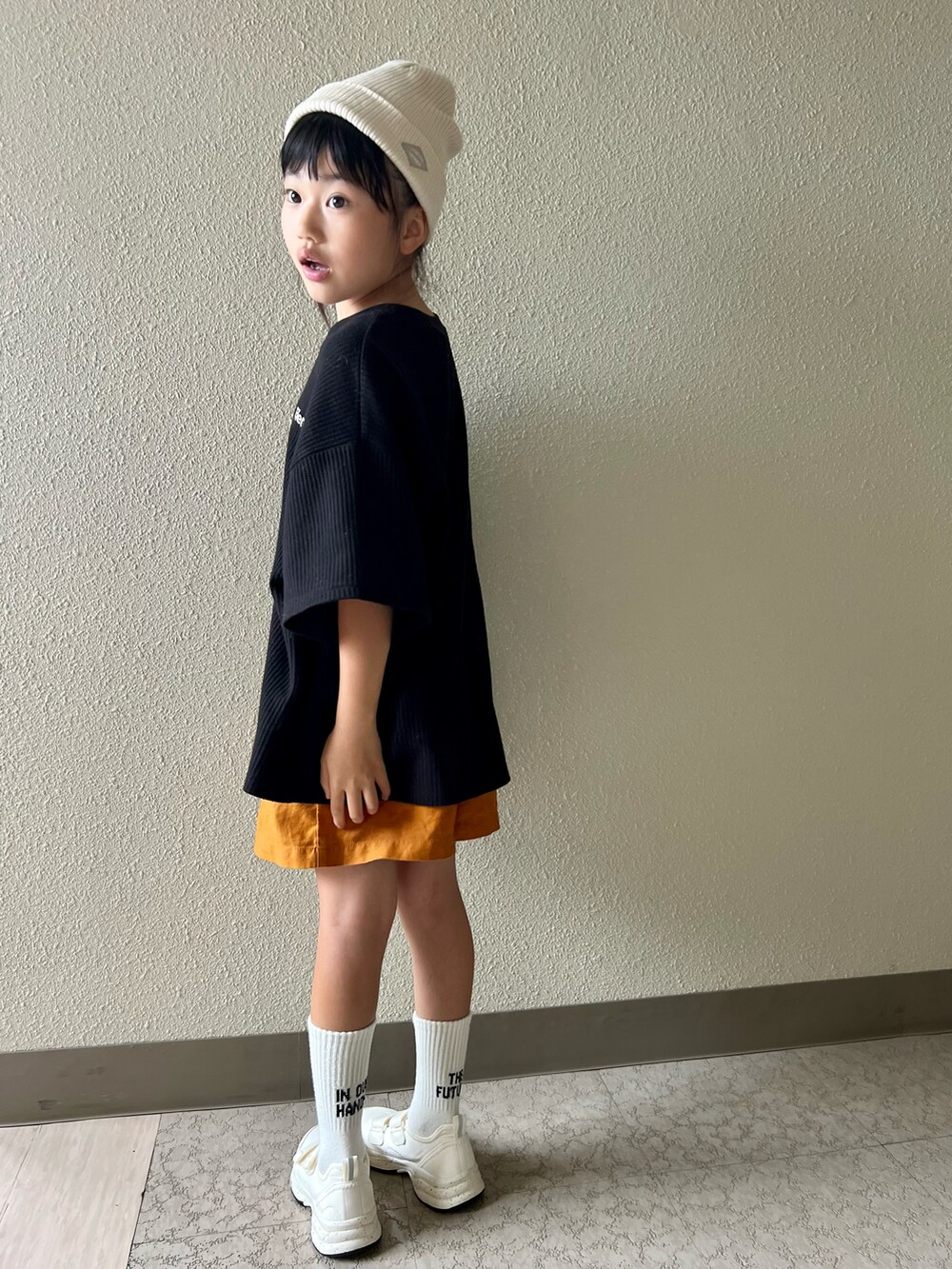 ブラック系のTシャツ/カットソー、オレンジ系のパンツ、ホワイト系のスニーカーを着用したキッズの春コーディネートの2枚目の写真