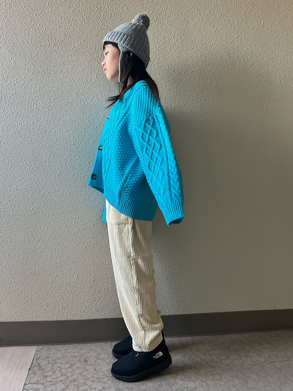 ブルー系のカーディガン/ボレロ、ホワイト系のその他パンツ、ブラック系のブーツを着用したキッズの冬コーディネートの4枚目の写真