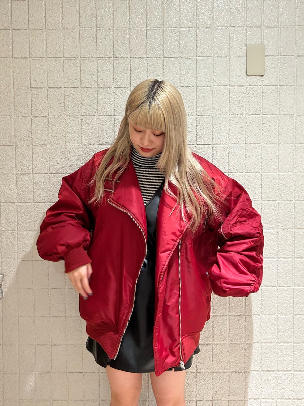 レッド系のMA-1、ブラック系のブーツ、ブラック系のジャンパースカートを着用したレディースの冬コーディネートの5枚目の写真