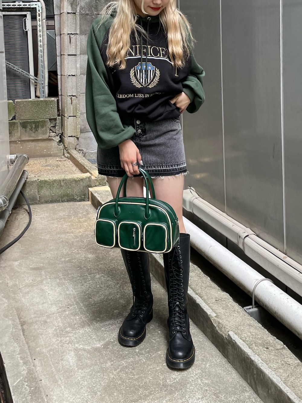 ブラック系のデニムパンツ、ブラック系のパーカー、グリーン系のボストンバッグを着用したレディースの秋コーディネートの2枚目の写真