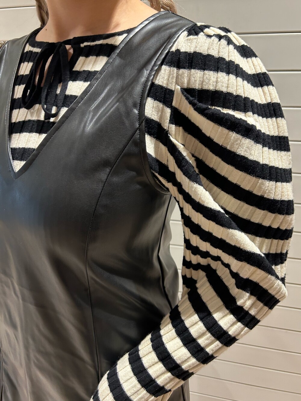 ホワイト系のニット/セーター、ブラック系のハンドバッグ、ブラック系のジャンパースカートを着用したレディースの冬コーディネートの7枚目の写真