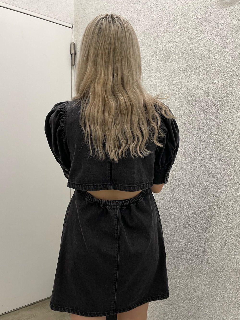 ブラック系のワンピース、ブラック系のブーツ、ブルー系のハンドバッグを着用したレディースの春コーディネートの3枚目の写真