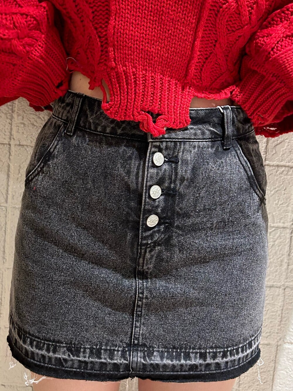 レッド系のニット/セーター、ブラック系のデニムパンツ、ブラック系のブーツを着用したレディースの冬コーディネートの6枚目の写真