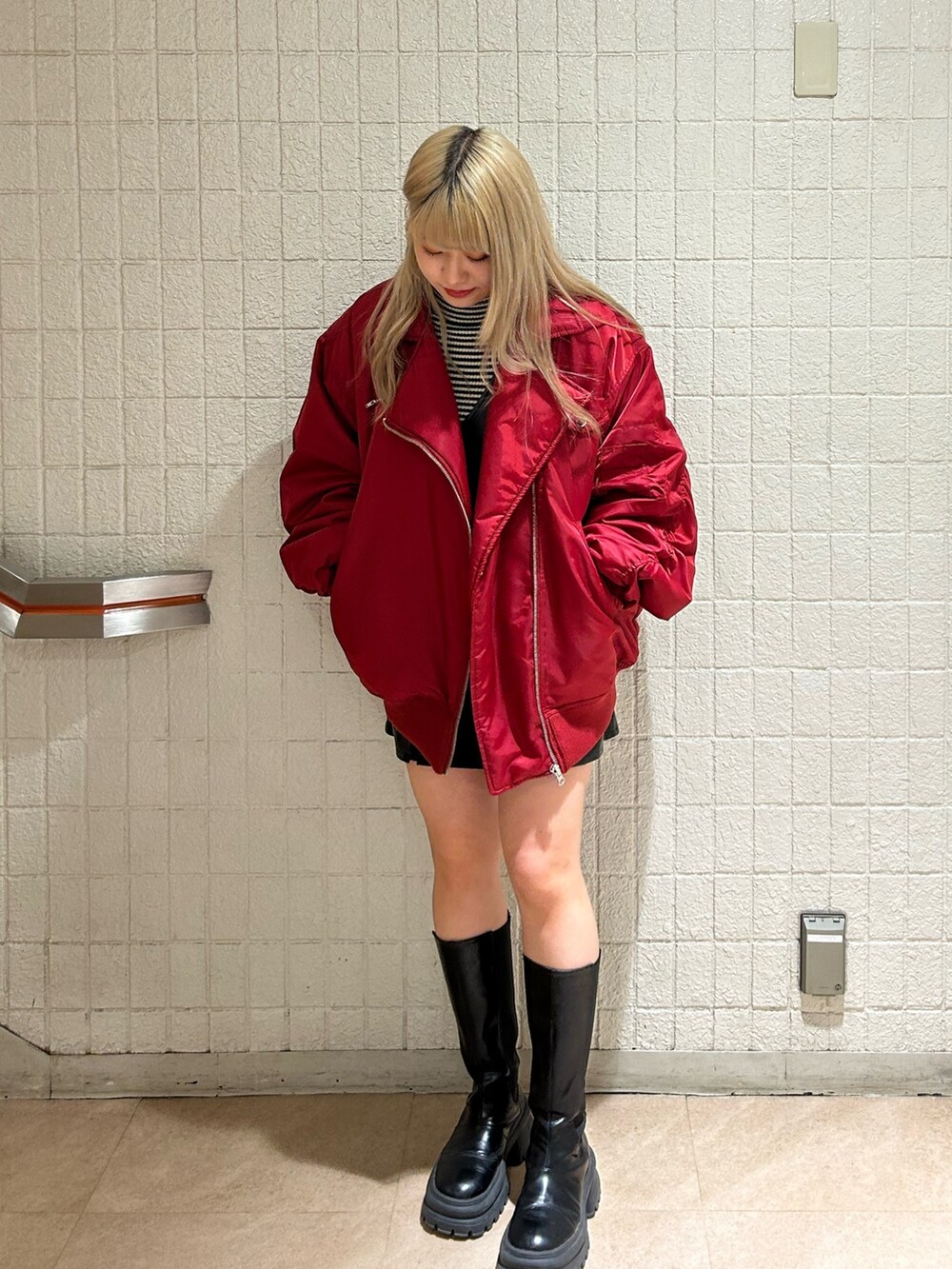 レッド系のMA-1、ブラック系のブーツ、ブラック系のジャンパースカートを着用したレディースの冬コーディネートの2枚目の写真