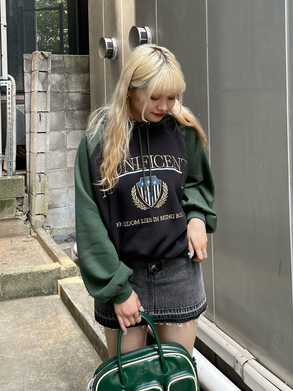 ブラック系のデニムパンツ、ブラック系のパーカー、グリーン系のボストンバッグを着用したレディースの秋コーディネートの3枚目の写真
