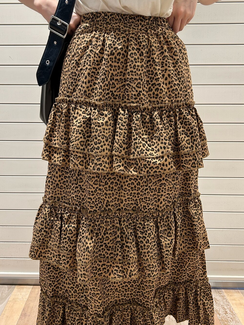 ブラウン系のスカート、ホワイト系のTシャツ/カットソー、ブラック系のショルダーバッグを着用したレディースの春コーディネートの7枚目の写真