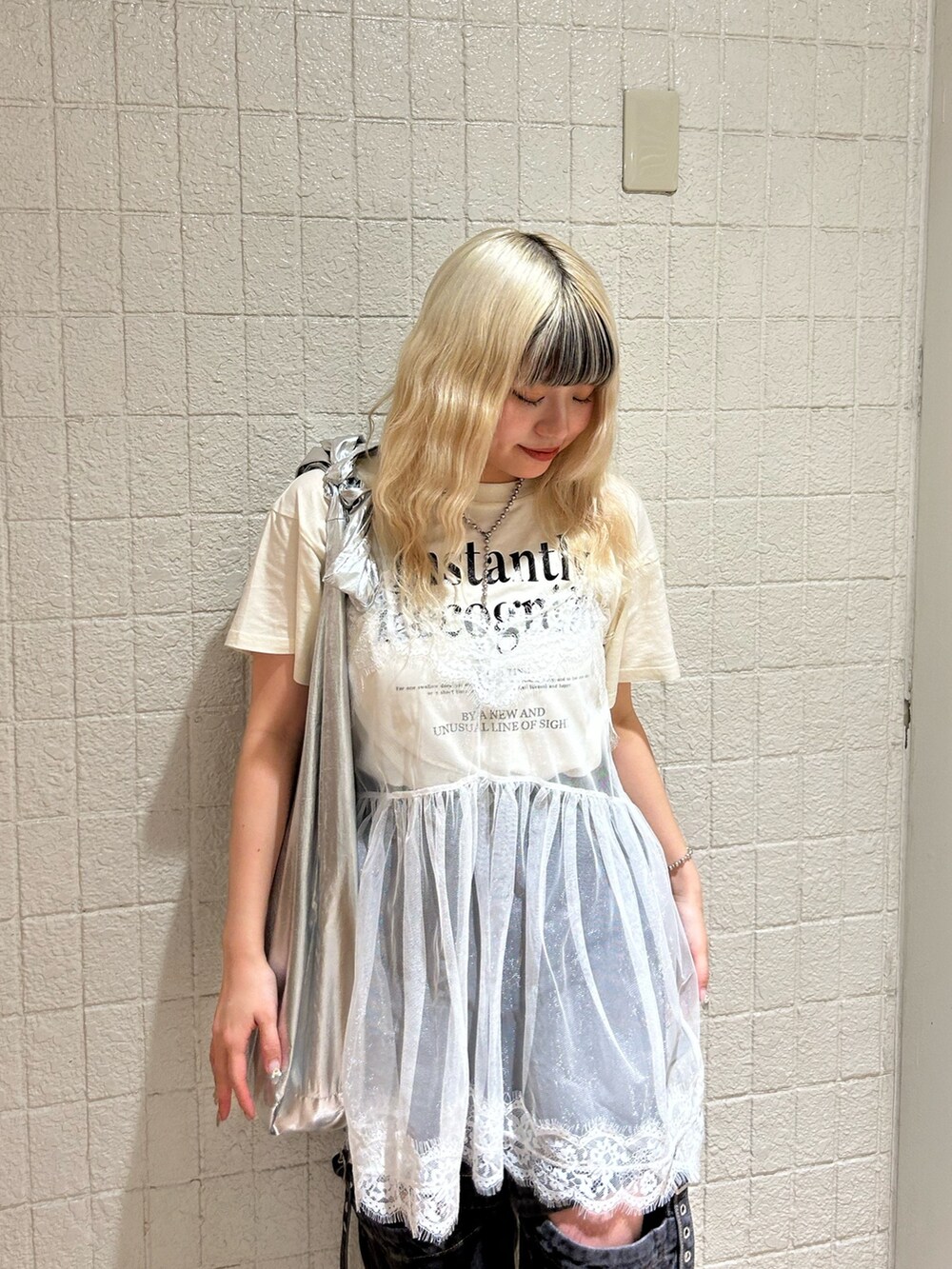 ホワイト系のTシャツ/カットソー、ブラック系のデニムパンツ、シルバー系のトートバッグを着用したレディースの春コーディネートの4枚目の写真