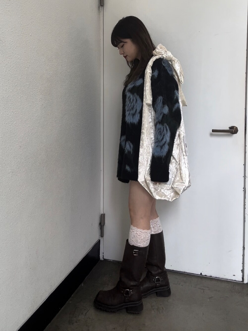 ホワイト系のトートバッグ、ブラック系のニット/セーター、ブラウン系のスカートを着用したレディースの秋コーディネートの5枚目の写真