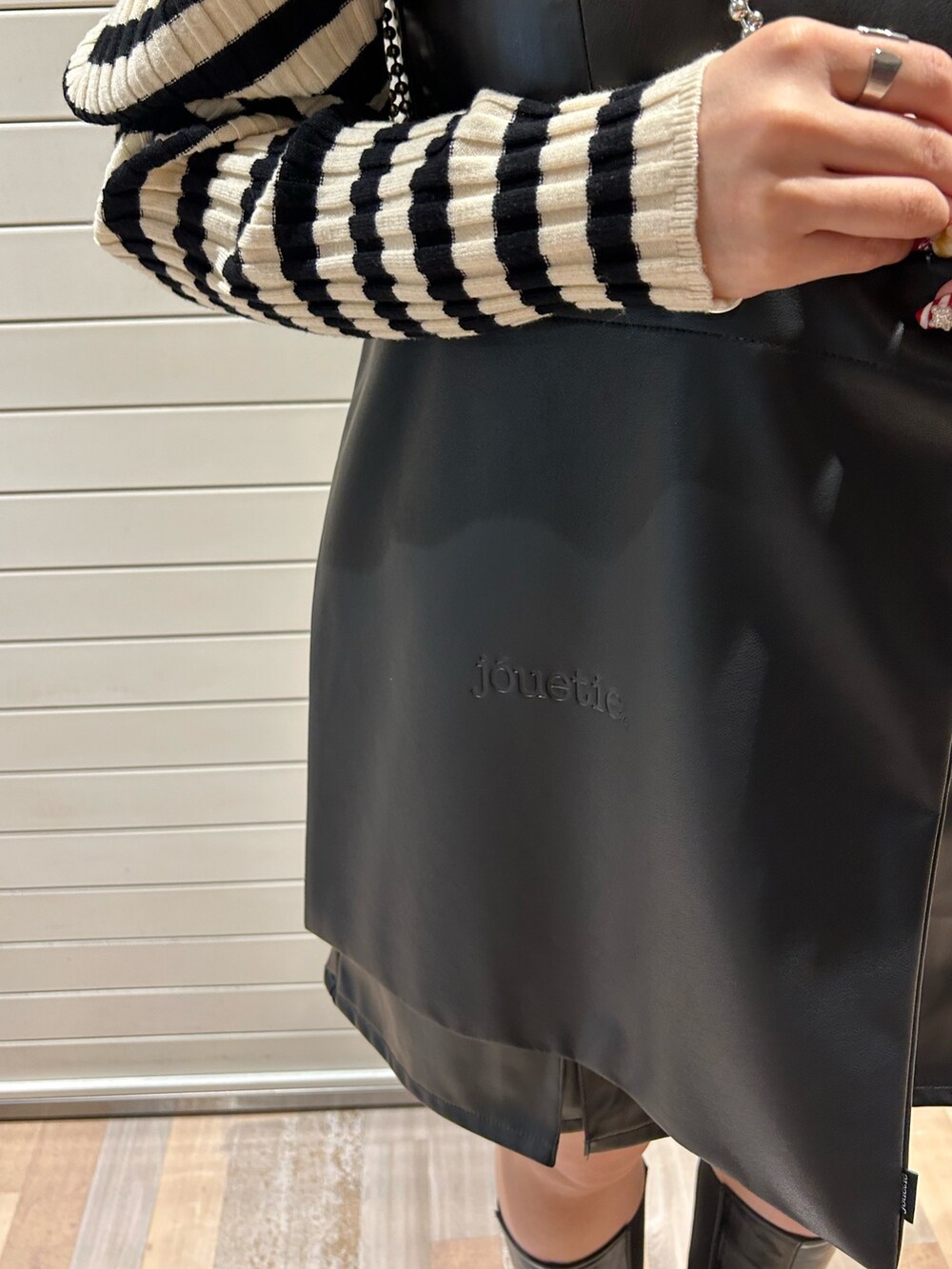 ホワイト系のニット/セーター、ブラック系のハンドバッグ、ブラック系のジャンパースカートを着用したレディースの冬コーディネートの8枚目の写真