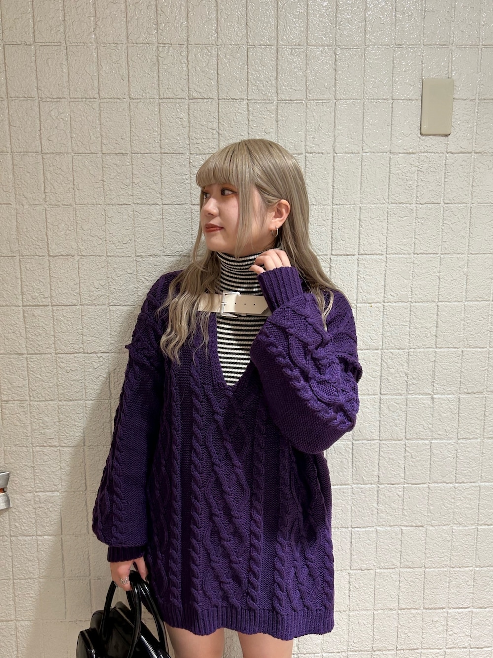 ブラック系のボストンバッグ、ブラック系のブーツ、パープル系のニット/セーターを着用したレディースの秋コーディネートの3枚目の写真