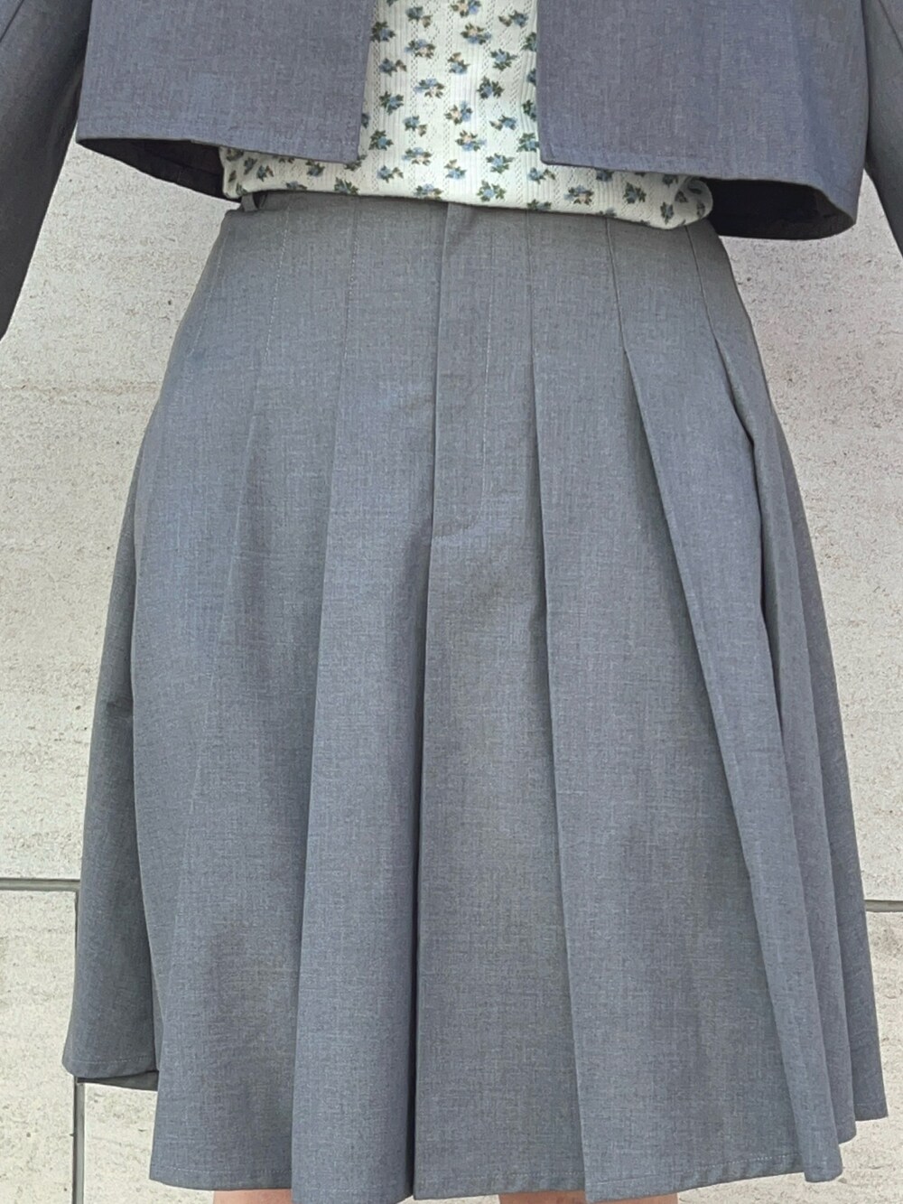 グレー系のテーラードジャケット、グレー系のスカート、ブラック系のブーツを着用したレディースの冬コーディネートの7枚目の写真