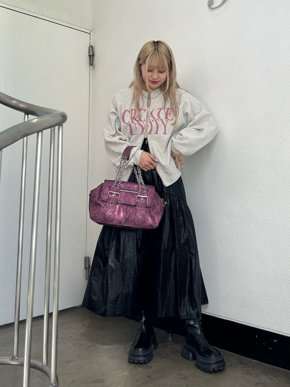 グレー系のスウェット、ブラック系のスカート、パープル系のハンドバッグを着用したレディースの秋コーディネートの3枚目の写真