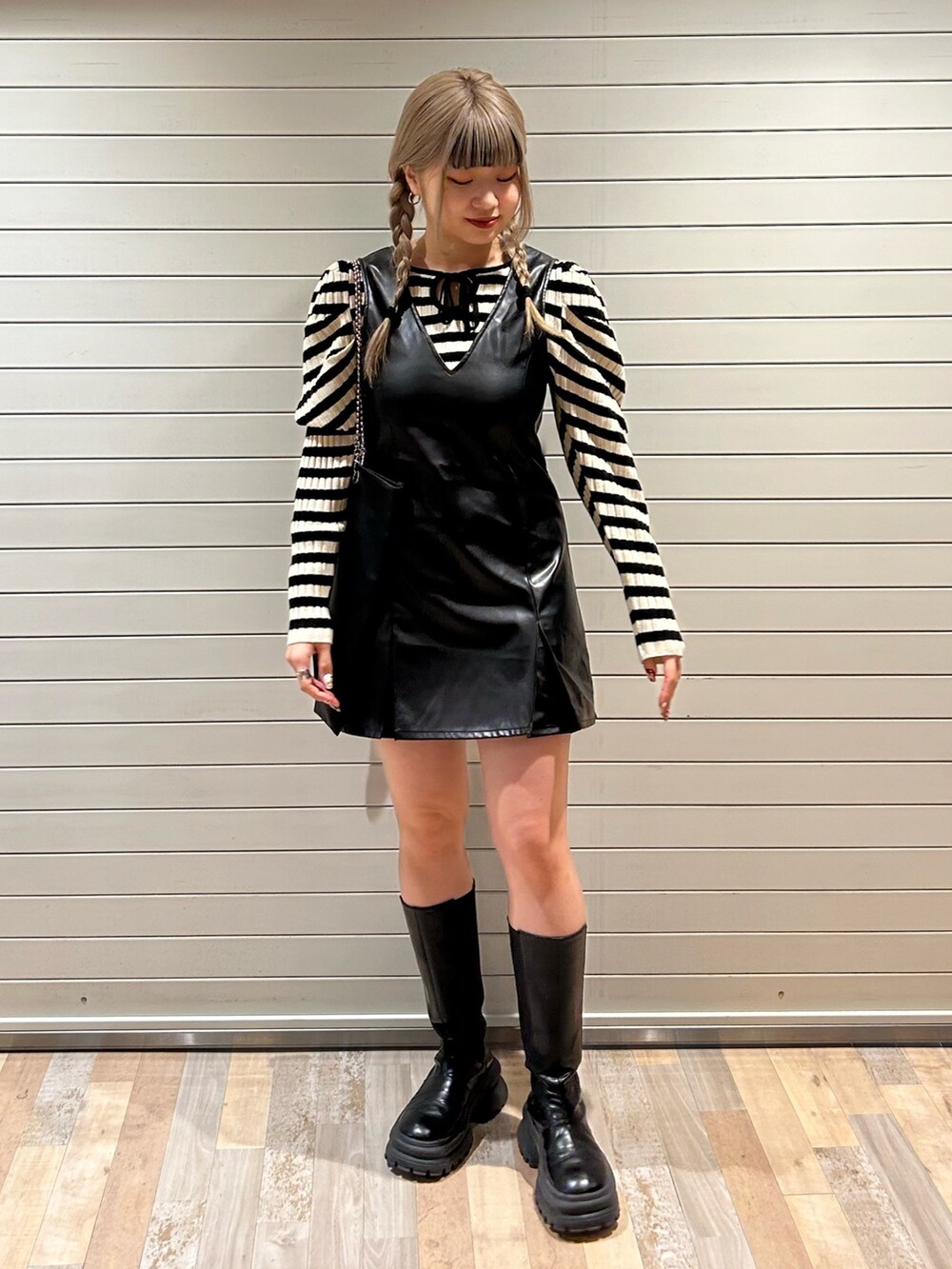 ホワイト系のニット/セーター、ブラック系のハンドバッグ、ブラック系のジャンパースカートを着用したレディースの冬コーディネートの2枚目の写真