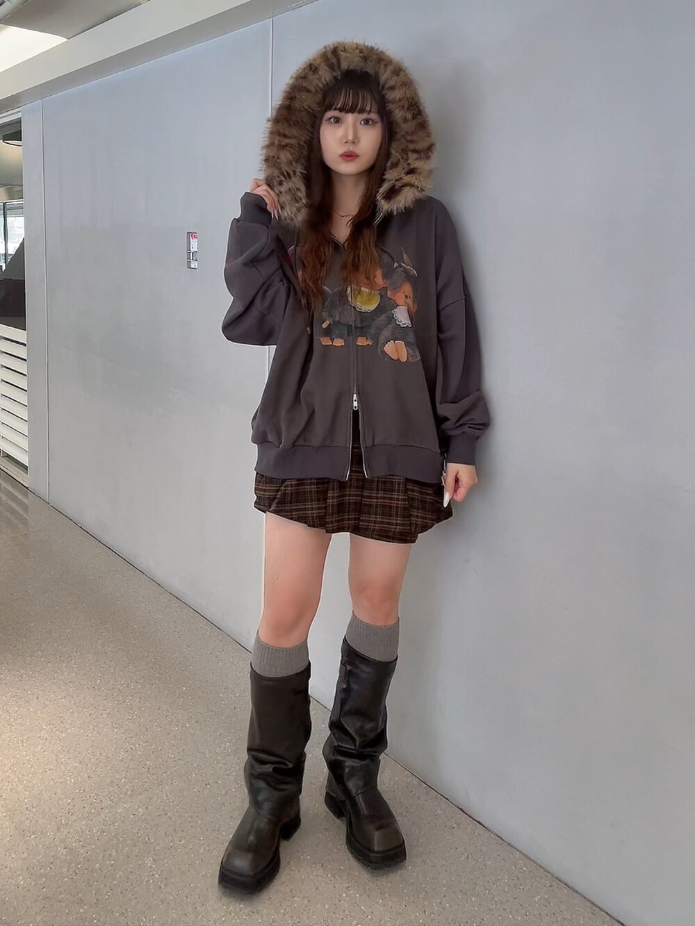 ブラウン系のスカート、ブラック系のパーカー、ブラック系のブーツを着用したレディースの秋コーディネートの2枚目の写真