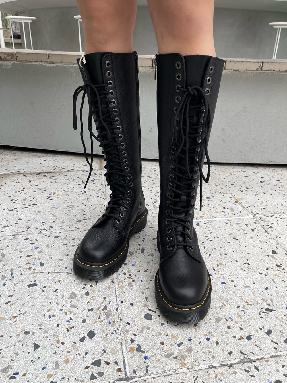 ホワイト系のブルゾン、オレンジ系のワンピース、ブラック系のブーツを着用したレディースの冬コーディネートの7枚目の写真