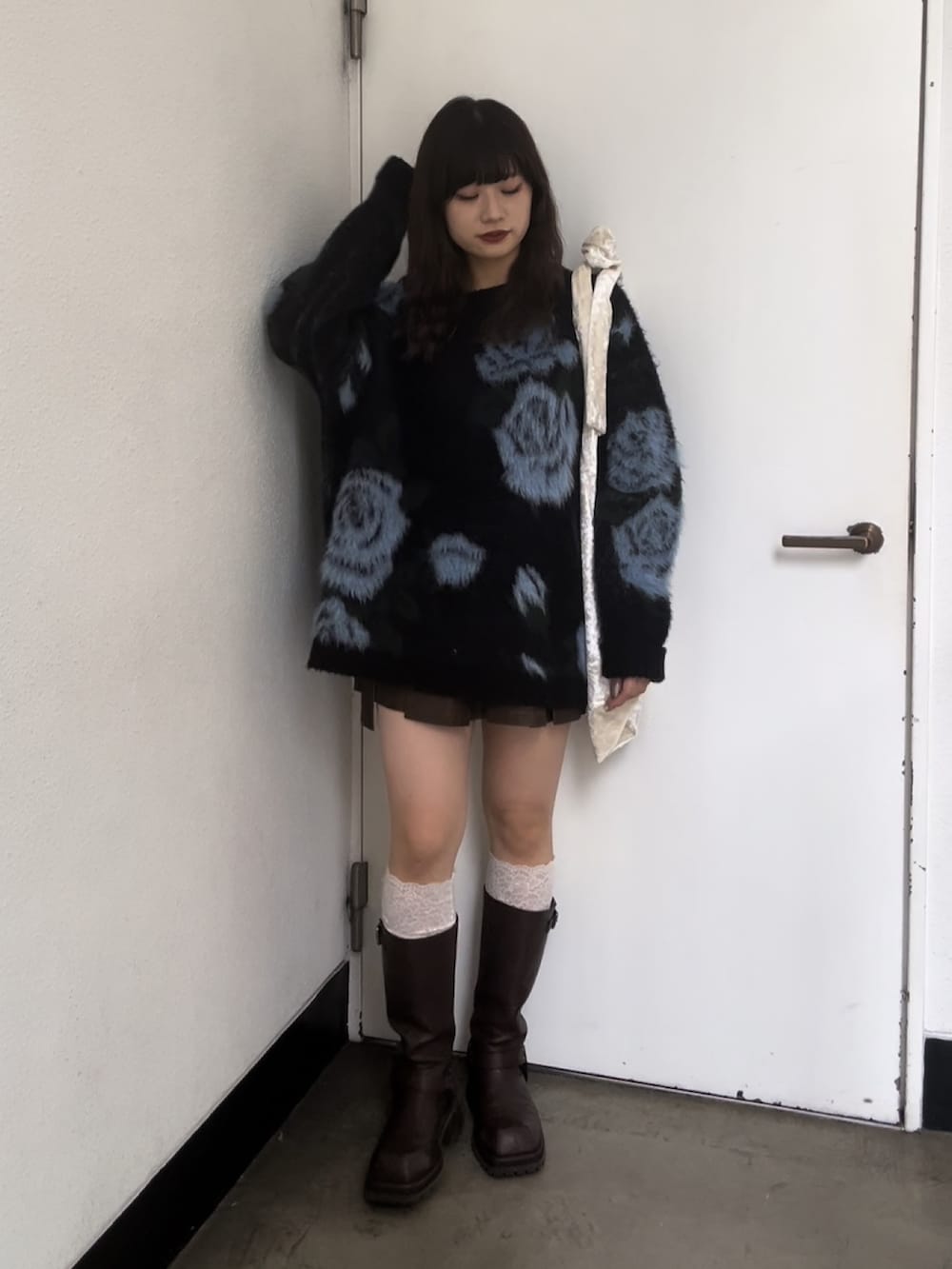 ホワイト系のトートバッグ、ブラック系のニット/セーター、ブラウン系のスカートを着用したレディースの秋コーディネートの3枚目の写真