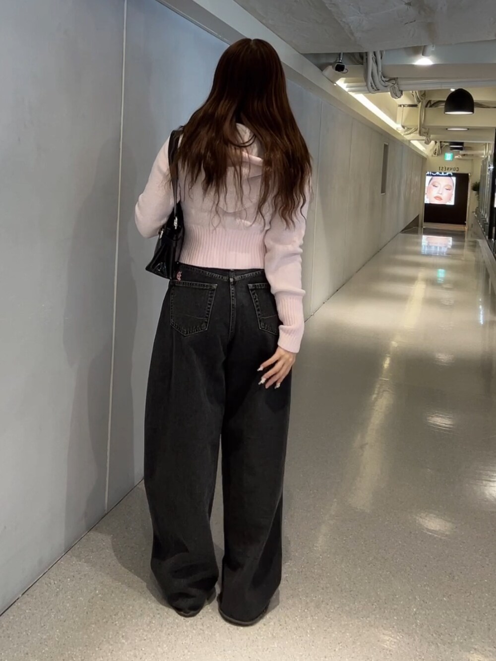 ピンク系のパーカー、ブラック系のデニムパンツを着用したレディースの冬コーディネートの3枚目の写真