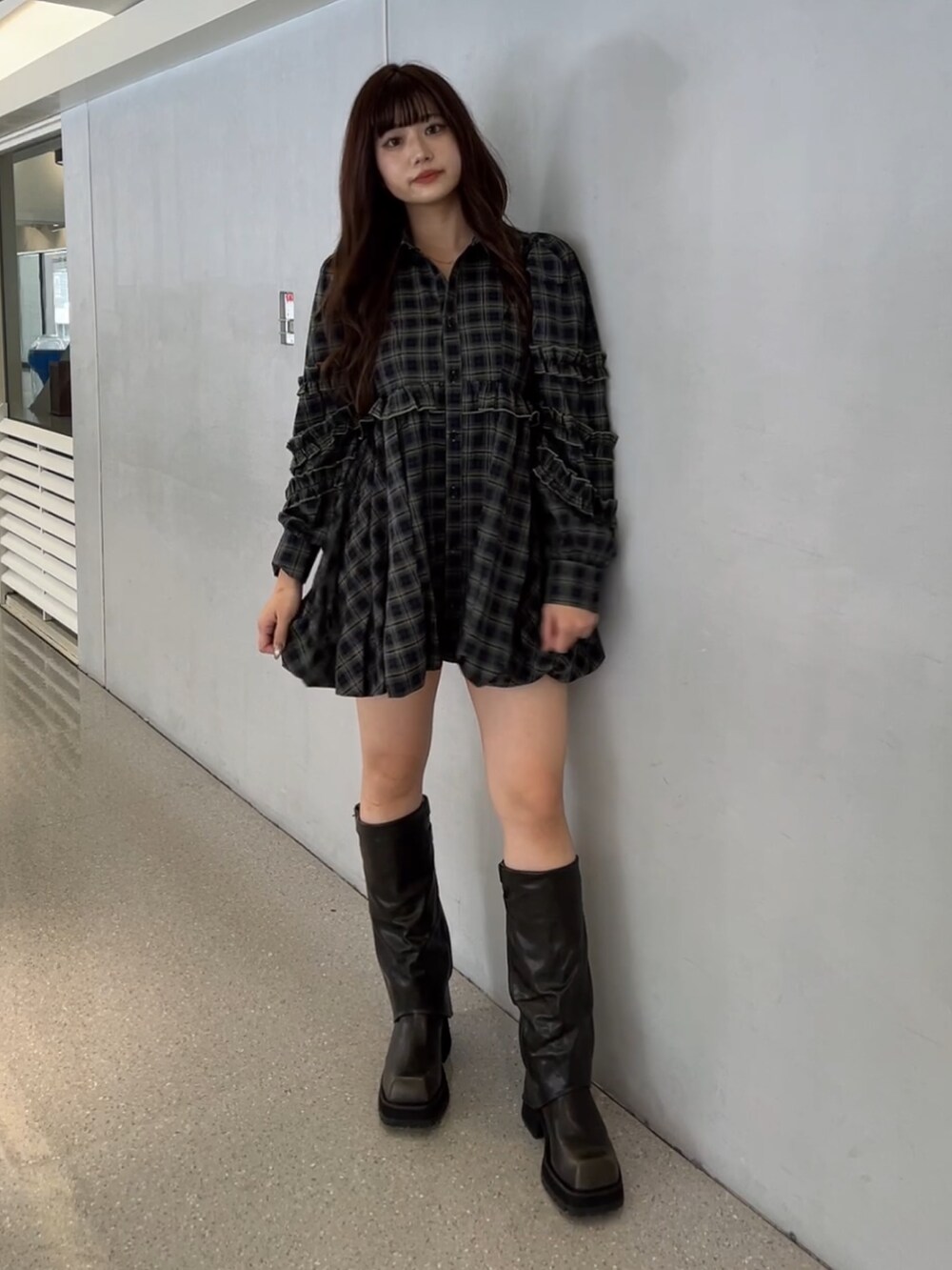 グリーン系のワンピース、ブラック系のブーツを着用したレディースの秋コーディネートの2枚目の写真