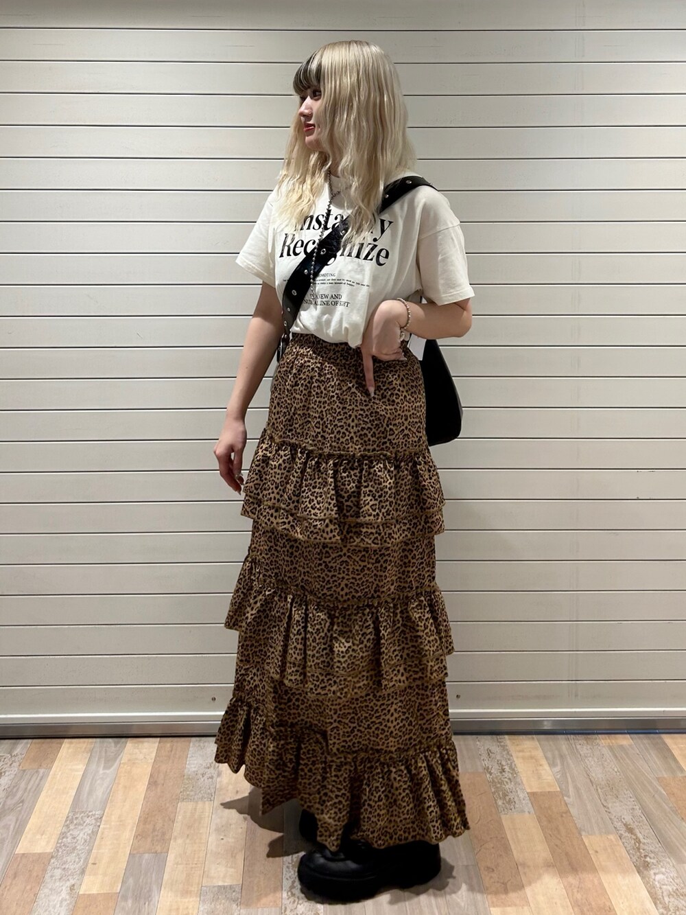 ブラウン系のスカート、ホワイト系のTシャツ/カットソー、ブラック系のショルダーバッグを着用したレディースの春コーディネートの2枚目の写真