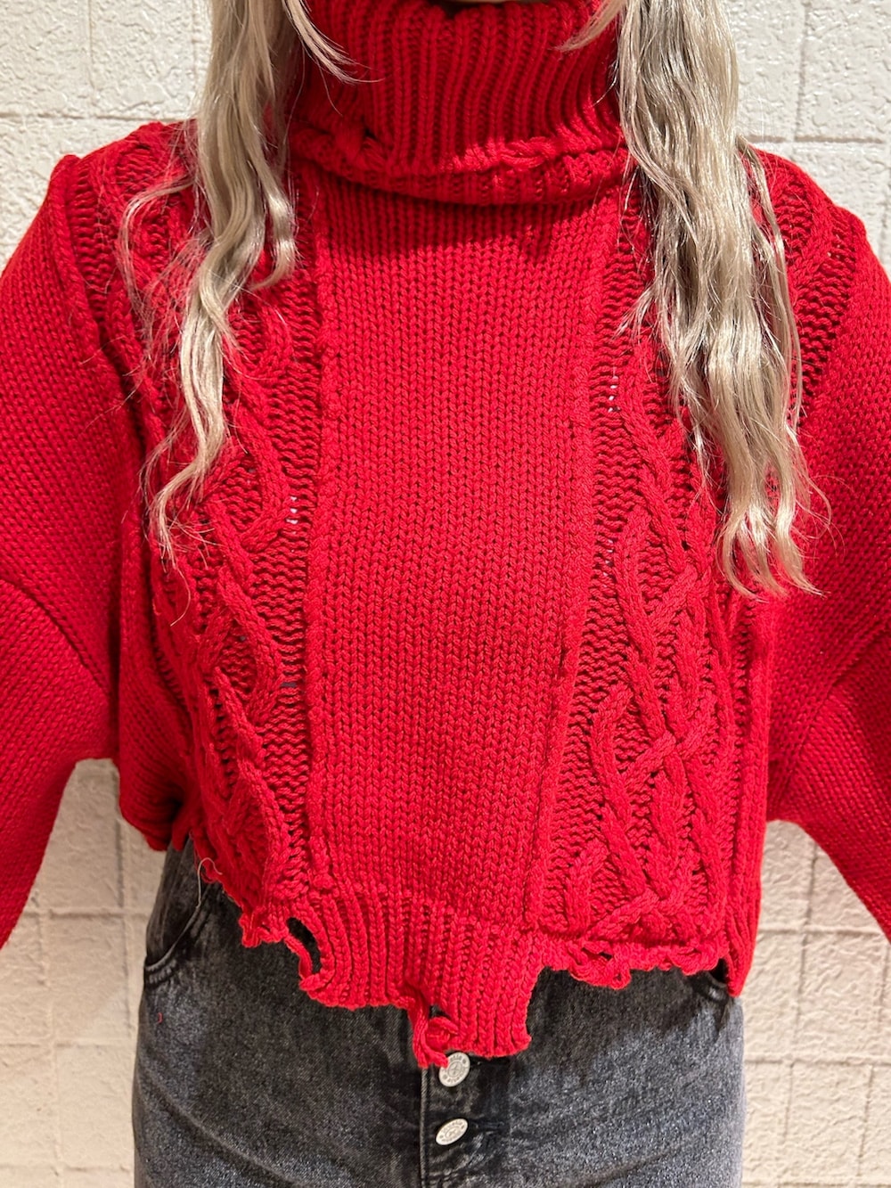 レッド系のニット/セーター、ブラック系のデニムパンツ、ブラック系のブーツを着用したレディースの冬コーディネートの4枚目の写真