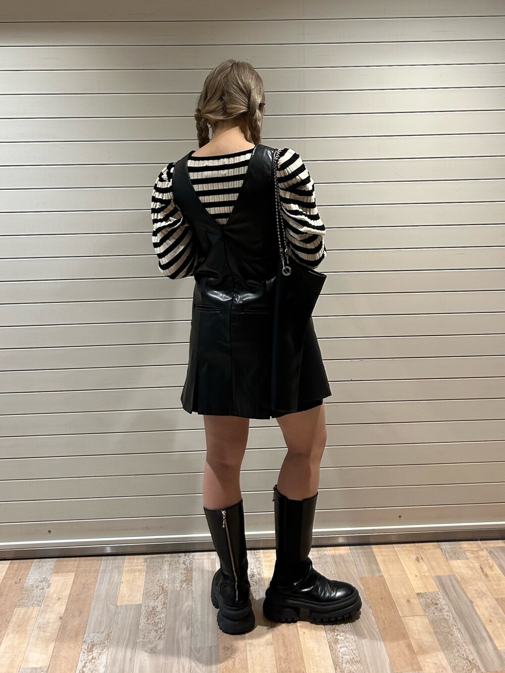 ホワイト系のニット/セーター、ブラック系のハンドバッグ、ブラック系のジャンパースカートを着用したレディースの冬コーディネートの3枚目の写真