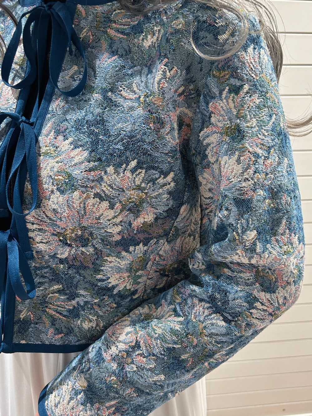 ブラック系のニット/セーター、ブルー系のノーカラージャケット、ホワイト系のスカートを着用したレディースの冬コーディネートの6枚目の写真