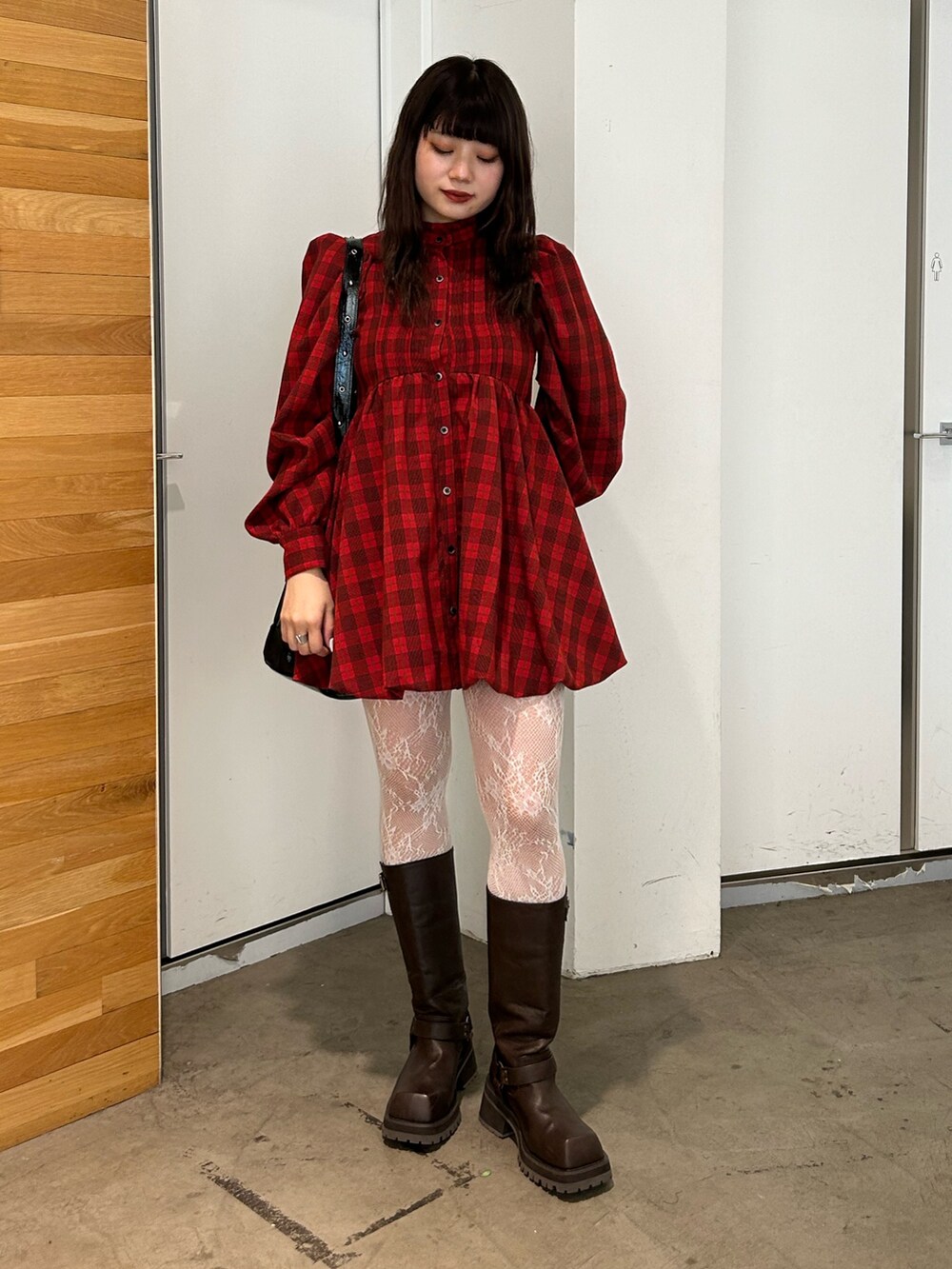 レッド系のワンピース、ブラウン系のブーツ、ブラック系のショルダーバッグを着用したレディースの夏コーディネートの3枚目の写真