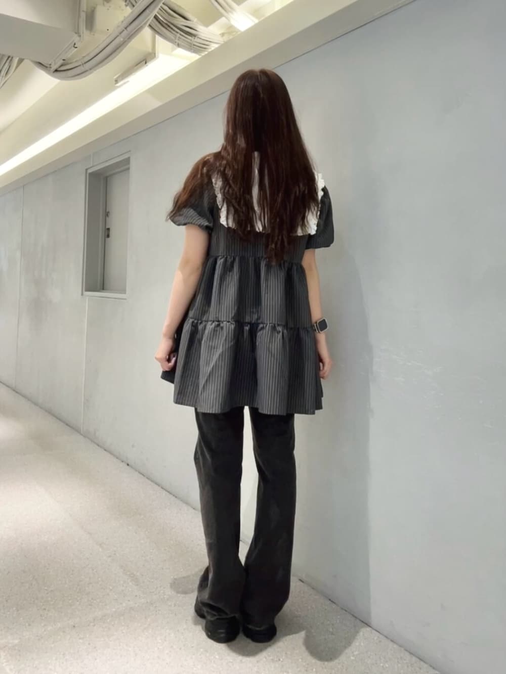 グレー系のワンピース、ブラック系のデニムパンツ、ブラック系のパンプスを着用したレディースの夏コーディネートの3枚目の写真