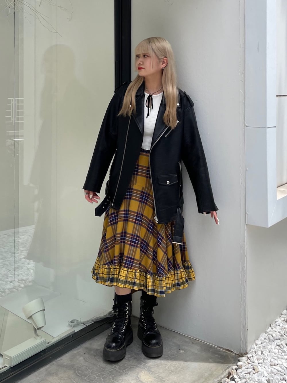 イエロー系のスカート、ブラック系のライダースジャケット、ホワイト系のTシャツ/カットソーを着用したレディースの秋コーディネートの2枚目の写真