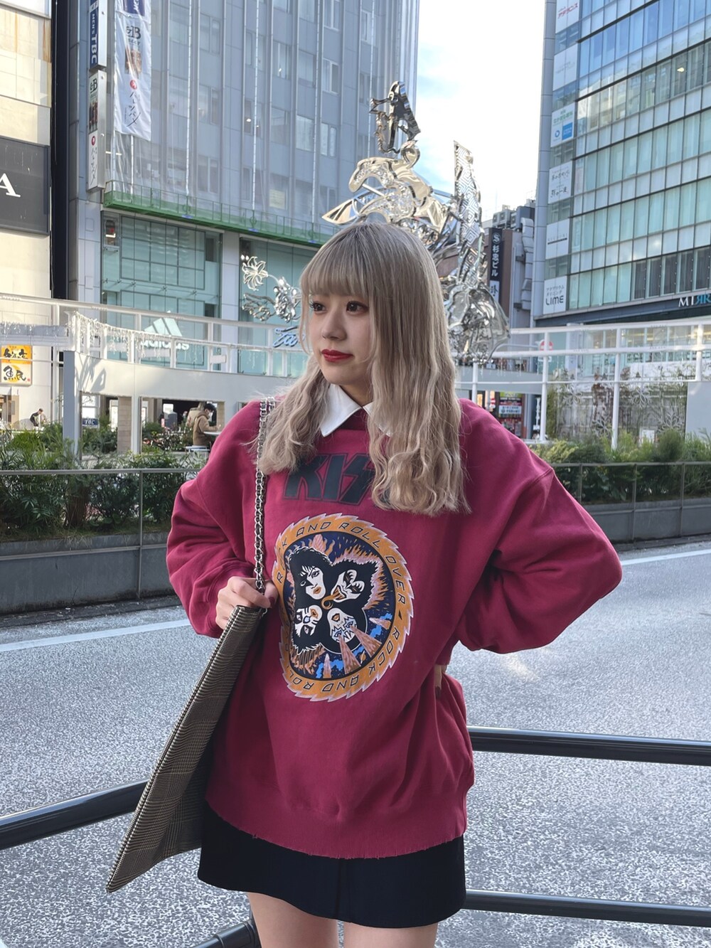 レッド系のスウェット、ブラック系のワンピース、ベージュ系のトートバッグを着用したレディースの冬コーディネートの3枚目の写真