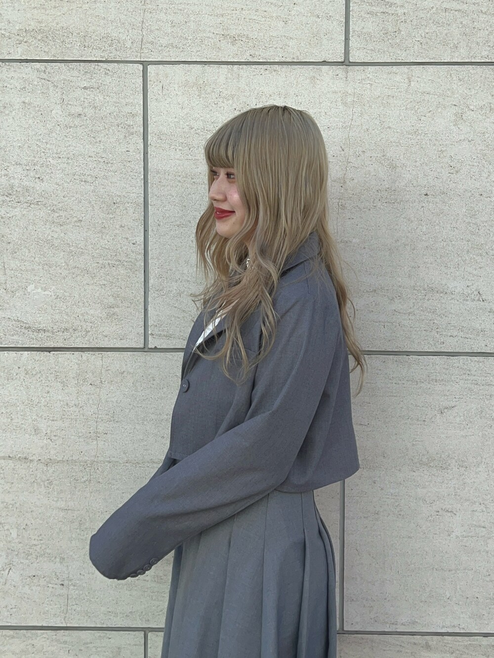 グレー系のテーラードジャケット、グレー系のスカート、ブラック系のブーツを着用したレディースの冬コーディネートの3枚目の写真