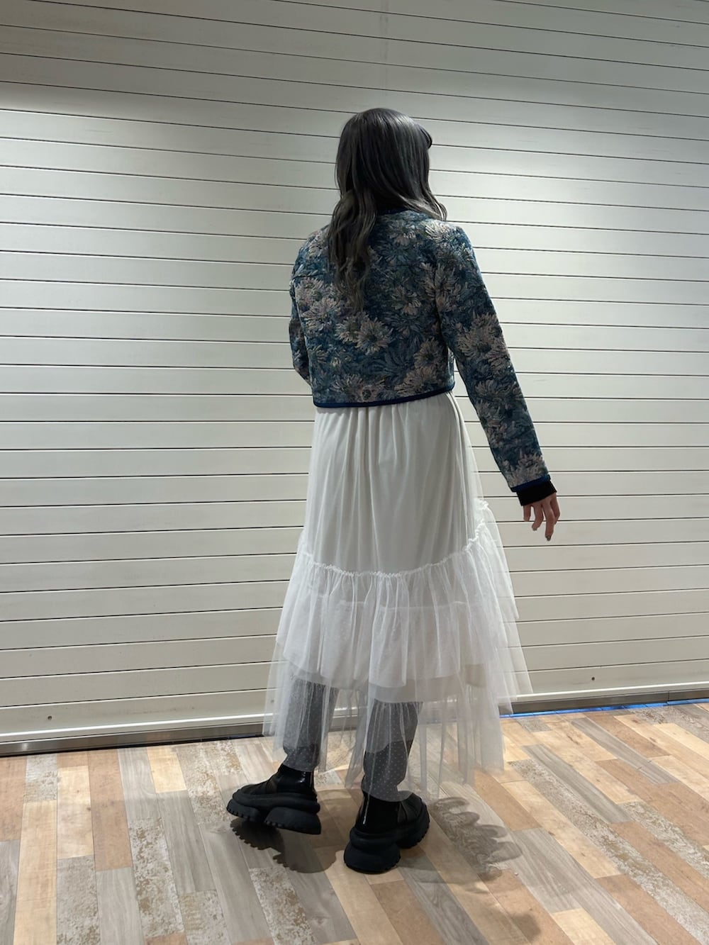 ブラック系のニット/セーター、ブルー系のノーカラージャケット、ホワイト系のスカートを着用したレディースの冬コーディネートの2枚目の写真