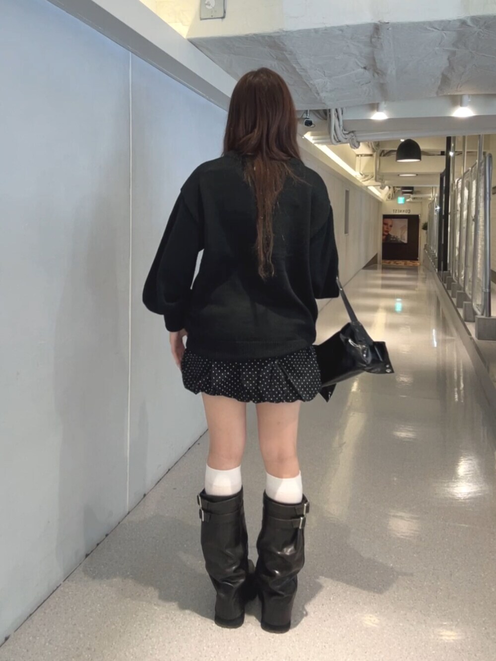 ブラック系のブーツ、ブラック系のスカート、ブラック系のショルダーバッグを着用したレディースの秋コーディネートの4枚目の写真