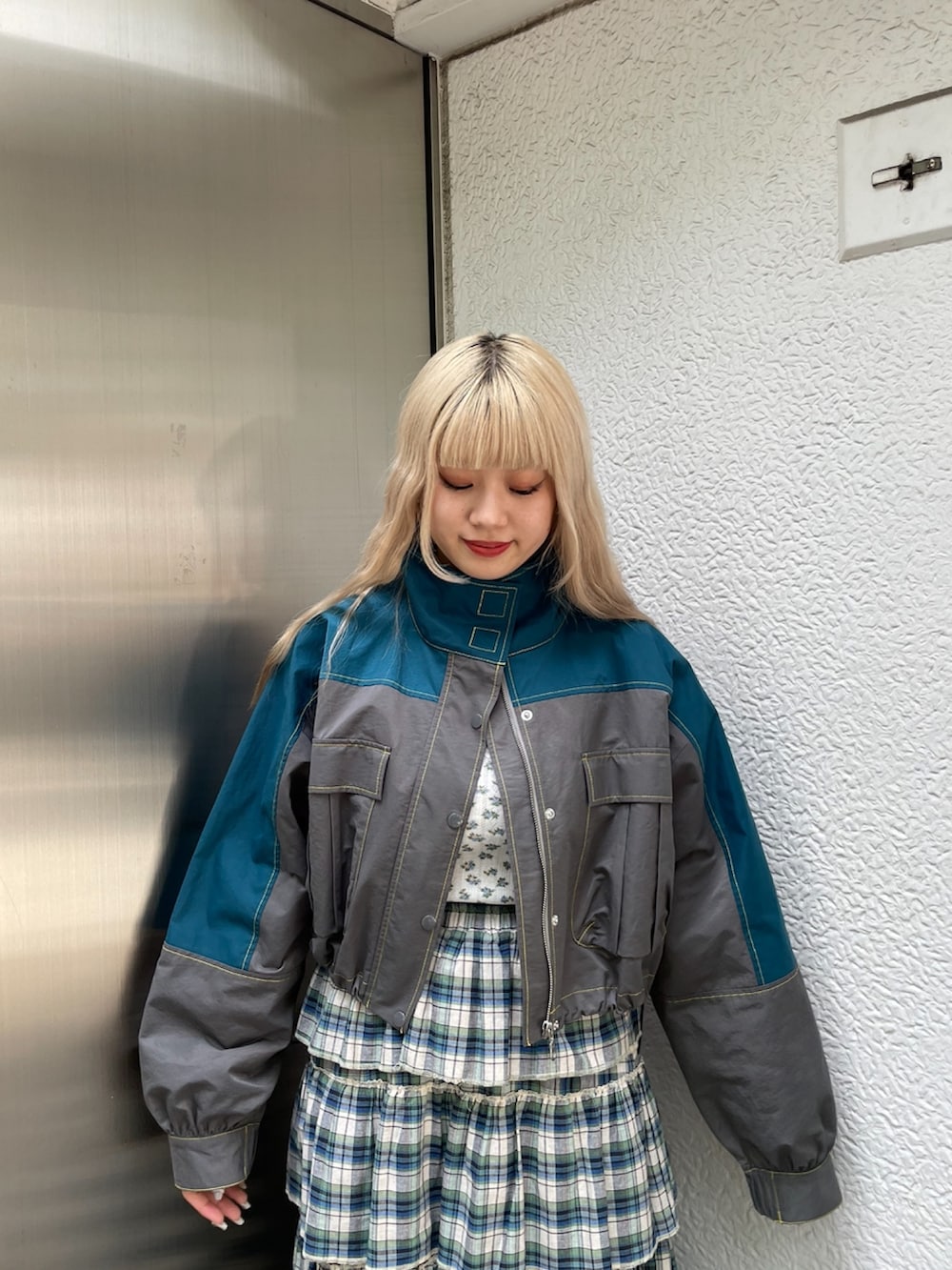 グレー系のブルゾン、グリーン系のスカート、ブラック系のその他シューズを着用したレディースの夏コーディネートの3枚目の写真