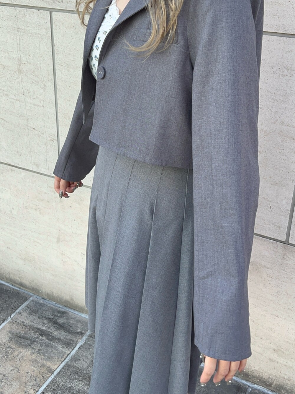 グレー系のテーラードジャケット、グレー系のスカート、ブラック系のブーツを着用したレディースの冬コーディネートの6枚目の写真