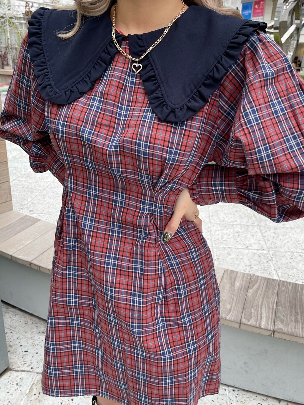 ホワイト系のブルゾン、オレンジ系のワンピース、ブラック系のブーツを着用したレディースの冬コーディネートの6枚目の写真