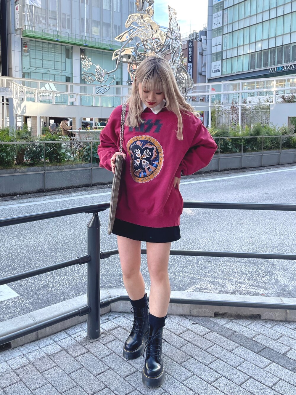 レッド系のスウェット、ブラック系のワンピース、ベージュ系のトートバッグを着用したレディースの冬コーディネートの2枚目の写真