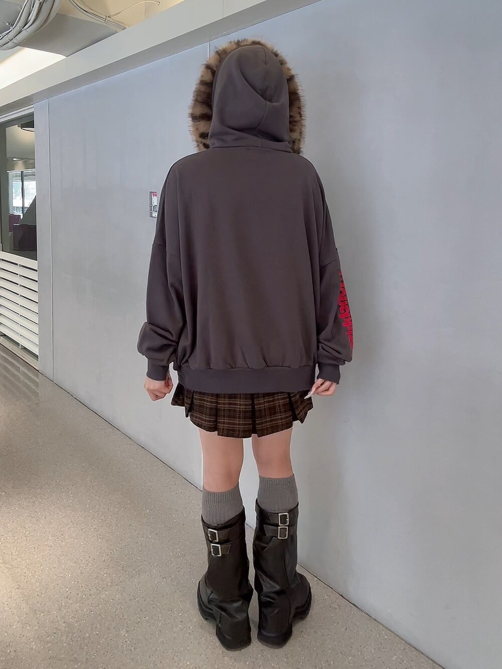 ブラウン系のスカート、ブラック系のパーカー、ブラック系のブーツを着用したレディースの秋コーディネートの4枚目の写真