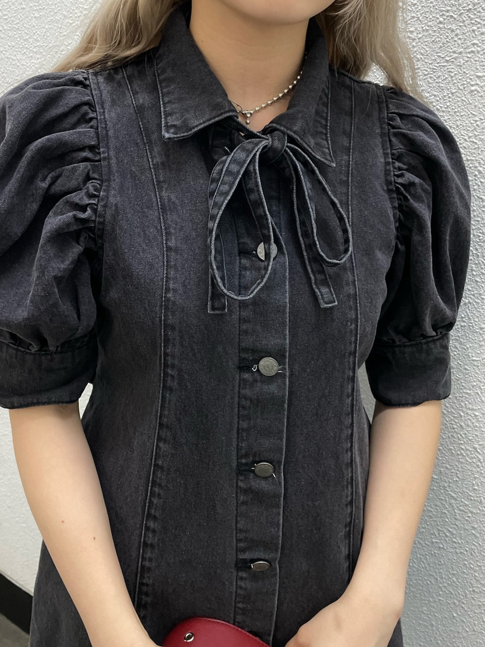 ブラック系のワンピース、ブラック系のブーツ、ブルー系のハンドバッグを着用したレディースの春コーディネートの4枚目の写真