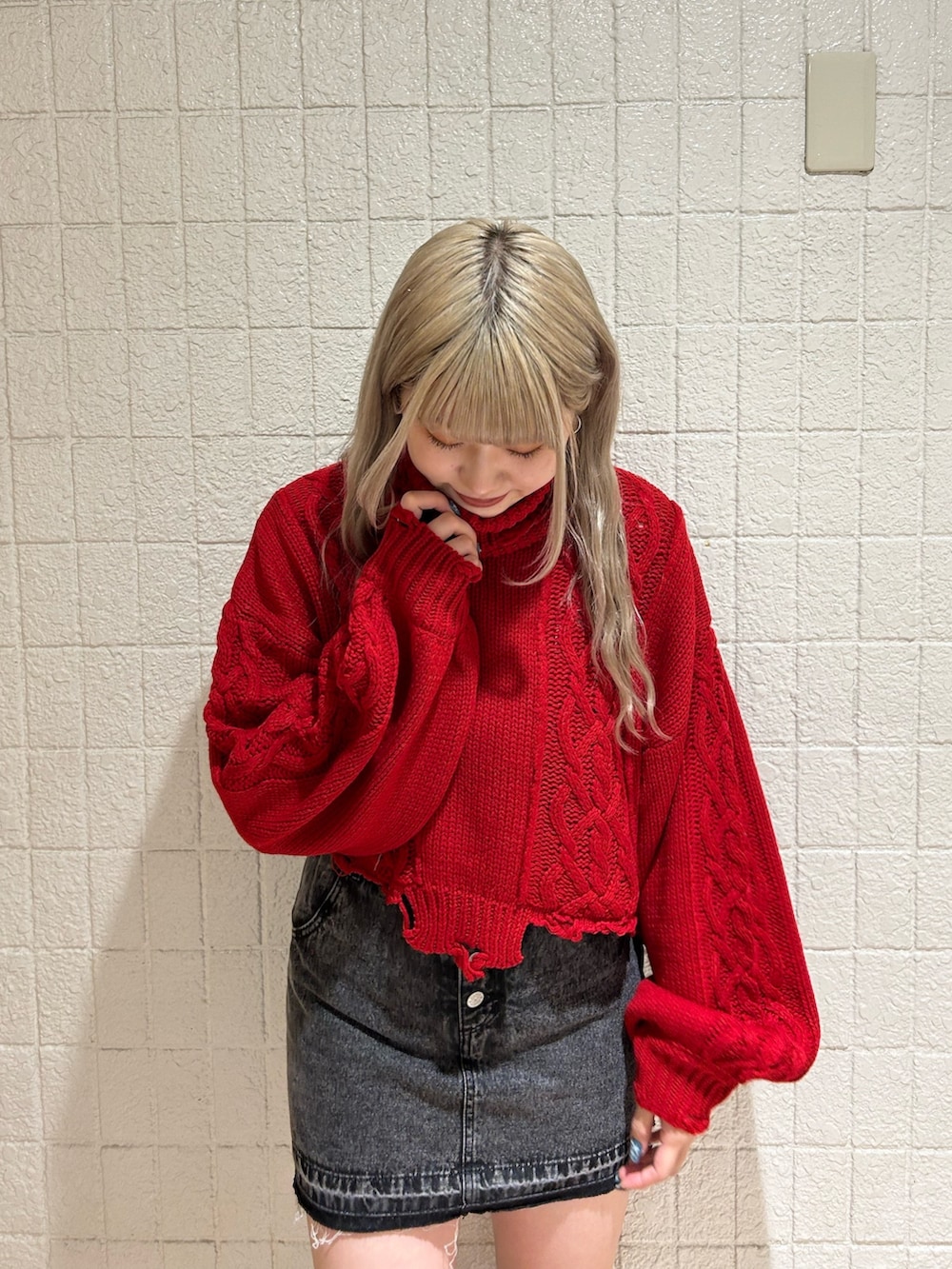 レッド系のニット/セーター、ブラック系のデニムパンツ、ブラック系のブーツを着用したレディースの冬コーディネートの2枚目の写真