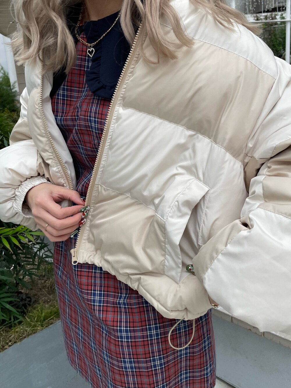 ホワイト系のブルゾン、オレンジ系のワンピース、ブラック系のブーツを着用したレディースの冬コーディネートの5枚目の写真