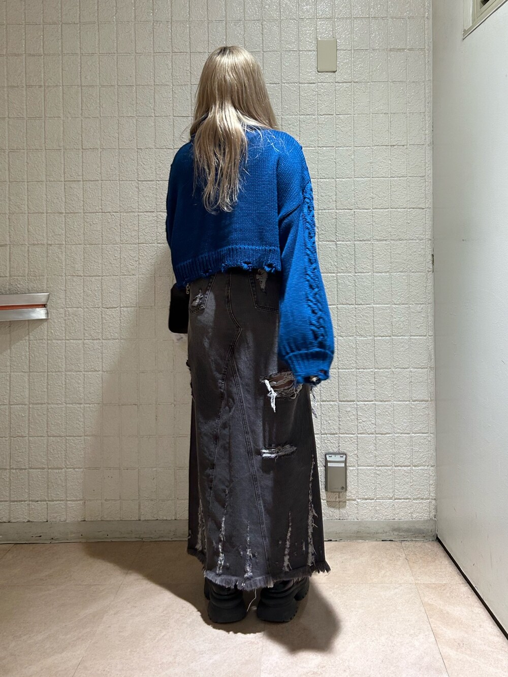 ブラック系のデニムスカート、ブルー系のニット/セーター、ブラック系のブーツを着用したレディースの冬コーディネートの3枚目の写真