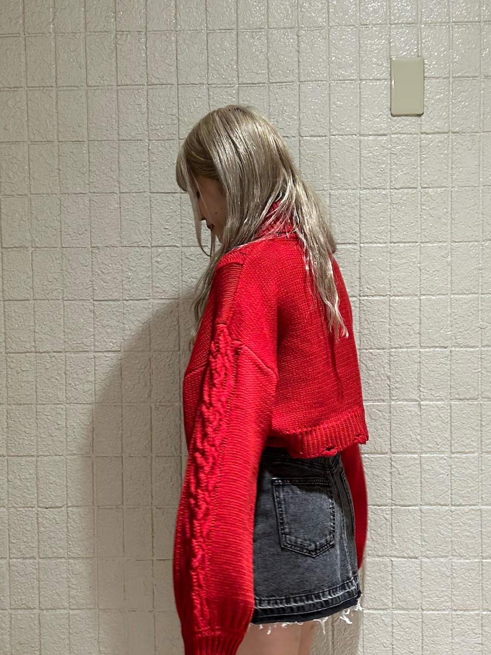 レッド系のニット/セーター、ブラック系のデニムパンツ、ブラック系のブーツを着用したレディースの冬コーディネートの3枚目の写真