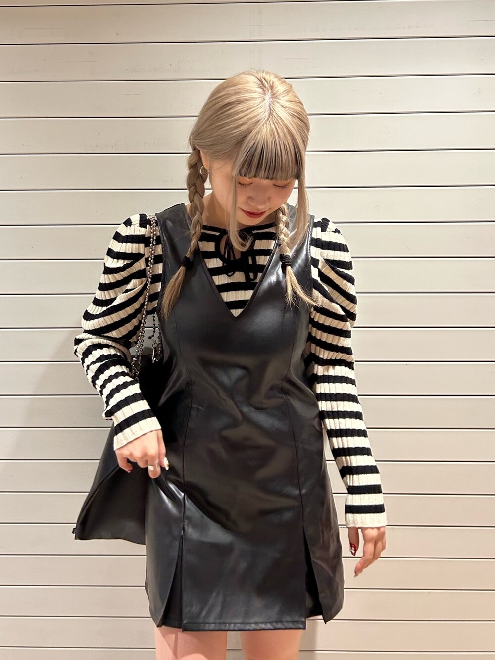 ホワイト系のニット/セーター、ブラック系のハンドバッグ、ブラック系のジャンパースカートを着用したレディースの冬コーディネートの4枚目の写真