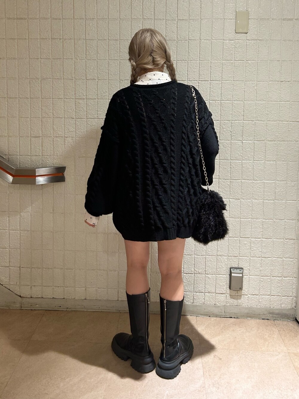 ブラック系のニット/セーター、ブラック系のブーツ、ホワイト系のシャツ/ブラウスを着用したレディースの冬コーディネートの3枚目の写真