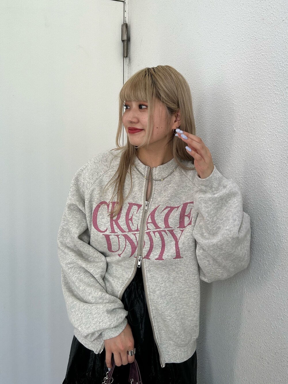 グレー系のスウェット、ブラック系のスカート、パープル系のハンドバッグを着用したレディースの秋コーディネートの5枚目の写真