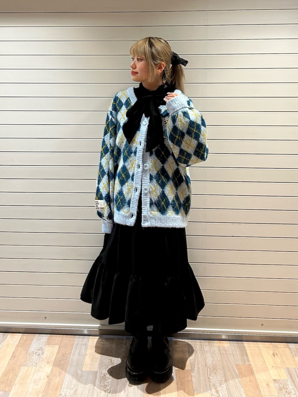 ブラック系のブーツ、ブルー系のカーディガン/ボレロ、ブラック系のワンピースを着用したレディースの秋コーディネートの2枚目の写真