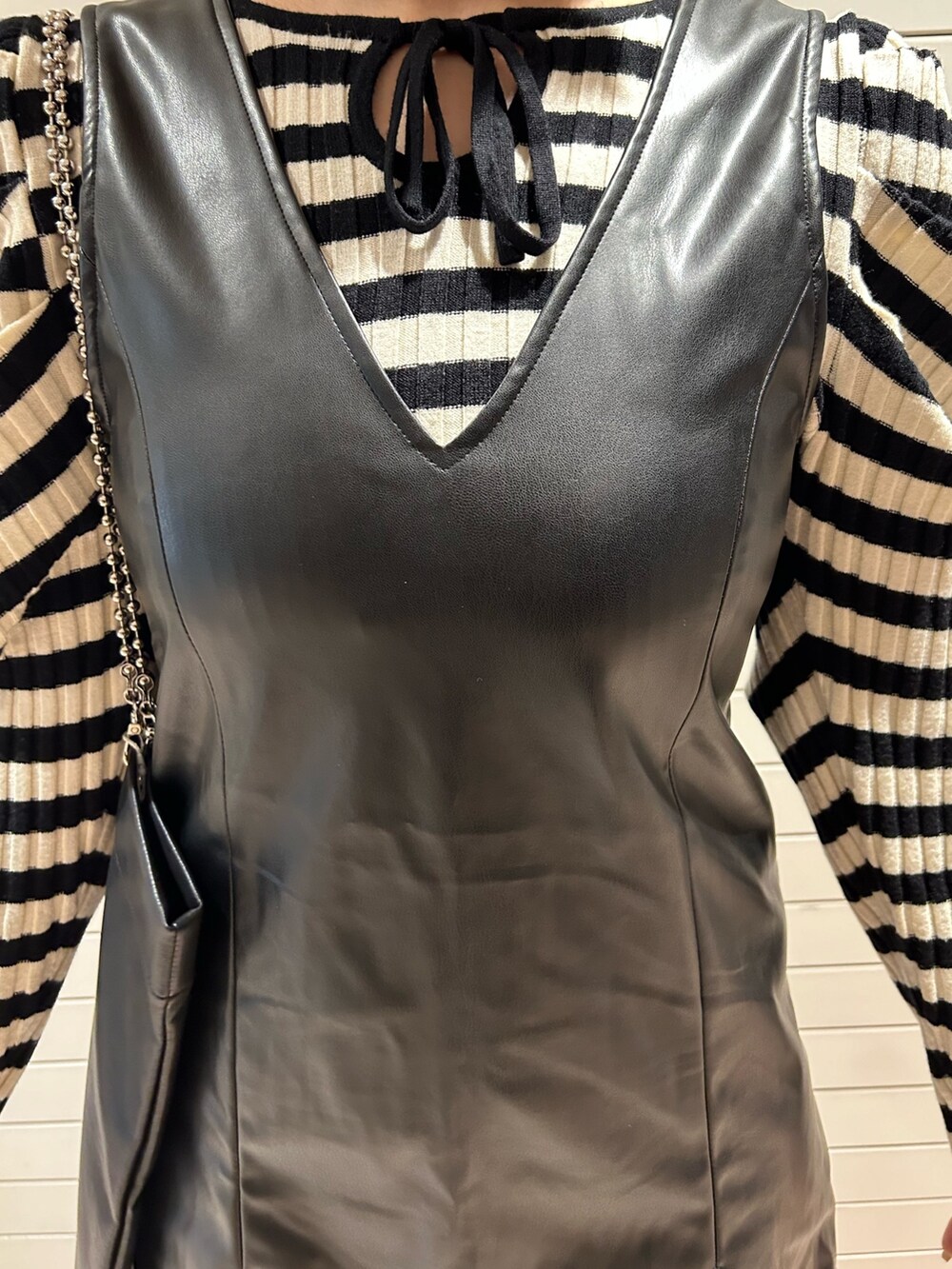 ホワイト系のニット/セーター、ブラック系のハンドバッグ、ブラック系のジャンパースカートを着用したレディースの冬コーディネートの6枚目の写真